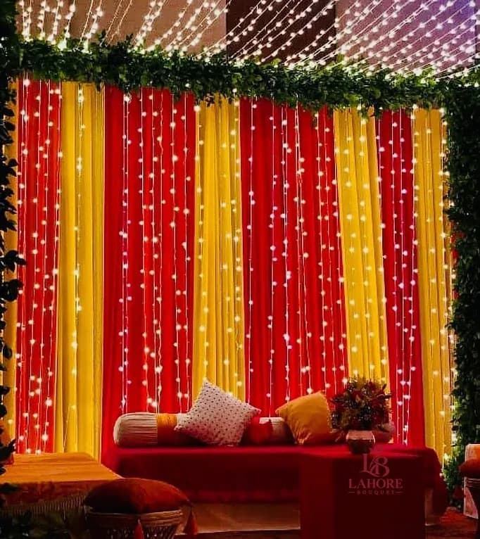 Elegant Wedding Backdrop with Red & Yellow Drapes and String Lights